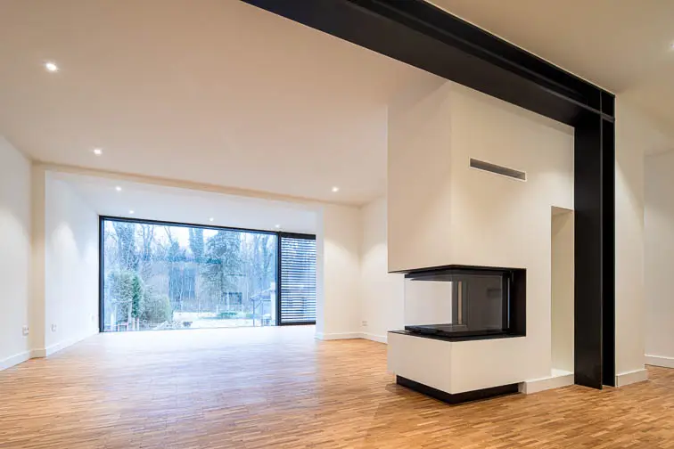 Der dreiseitige Kamin und das Stahlportal verbinden den Wohn- mit dem Essbereich