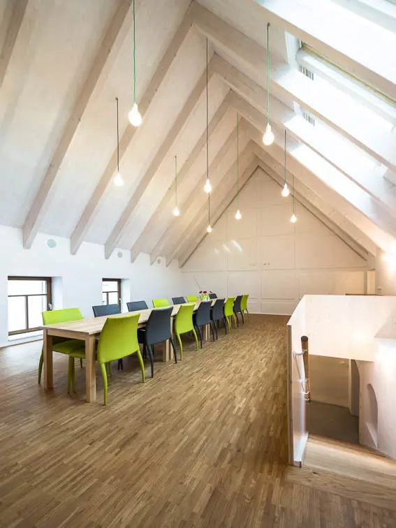 Sichtbare Sparren und eine Schalung aus Dreischichtplatten pr&auml;gen das Dach des Mehrzweckraums