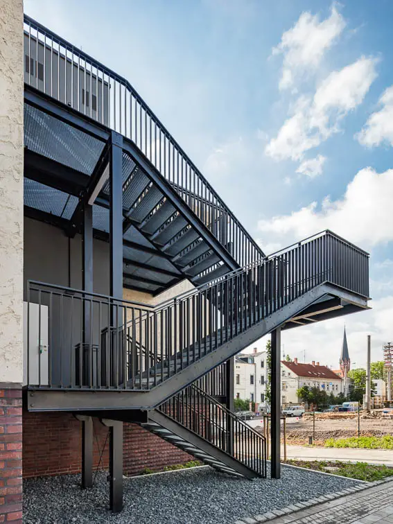 Ein zweiter baulicher Rettungsweg - ausgef&uuml;hrt als Stahltreppe - findet in einer unauff&auml;lligen Geb&auml;udenische Platz