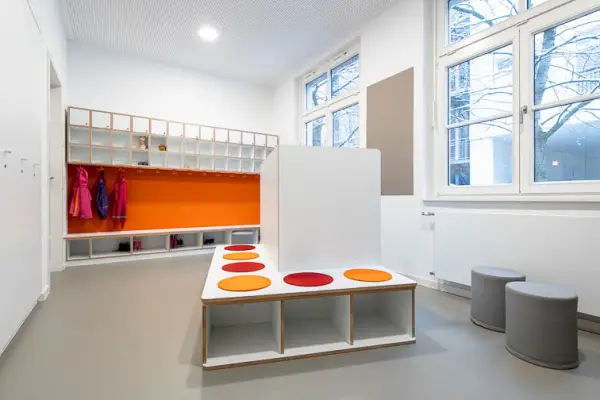 Innenraumperspektive der Garderobe mit Einbaum&ouml;beln und farblichen Akzenten in Orange- und Rott&ouml;nen